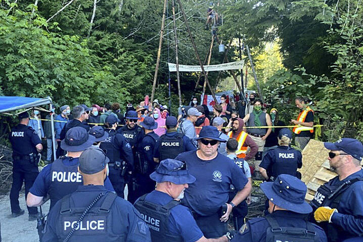 RCMP officers and protesters face off at a camp in Fairy Creek with tripod structures visible in the background. (Submitted by BC RCMP)