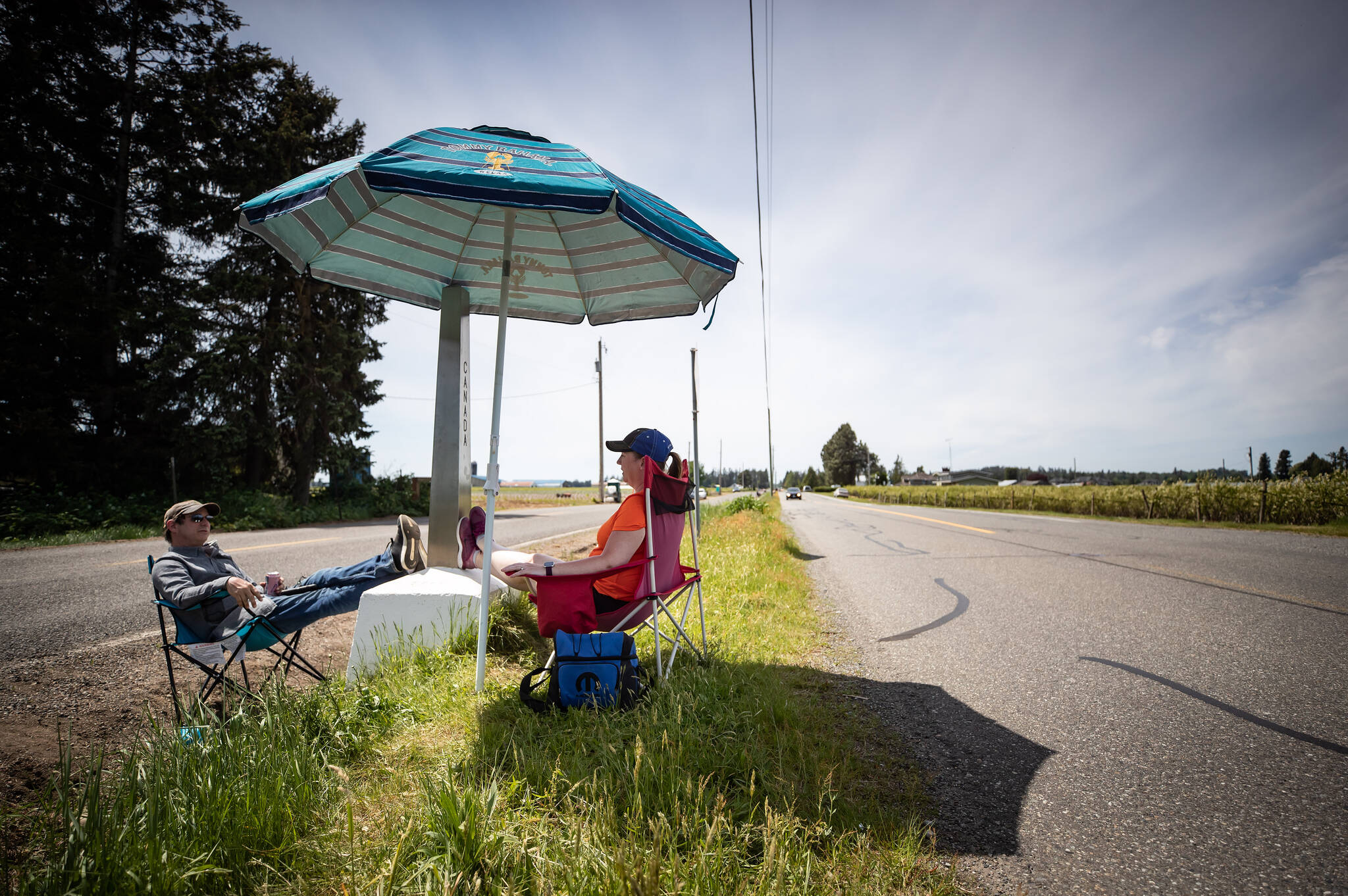 Engaged couple Rob Sensel, left, of Mount Vernon, Wash., and Kathryn Bell Lewis, of Richmond, B.C., spend time together separated by a ditch along the Canada-U.S. border, in Abbotsford, B.C., on Sunday, May 10, 2020. The closure of the Canada-U.S. border to non-essential travel has been extended another month, the U.S. announced Sept. 20. THE CANADIAN PRESS/Darryl Dyck