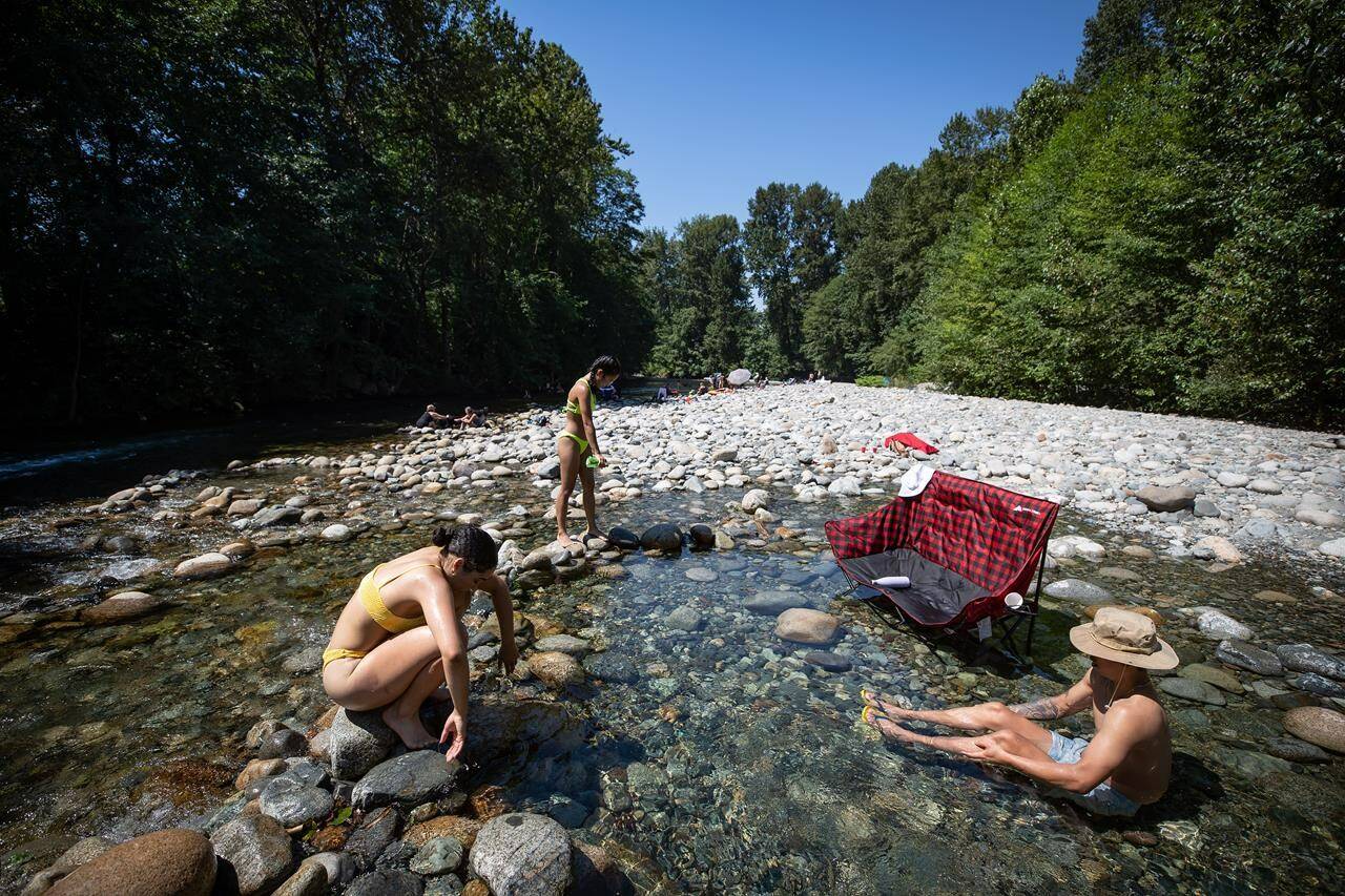 Sarah De Francesco, left, Albert Huynh, right, and Leanne Opuyes, back left, cool off in the frigid Lynn Creek water in North Vancouver, B.C., on Monday, June 28, 2021. THE CANADIAN PRESS/Darryl Dyck