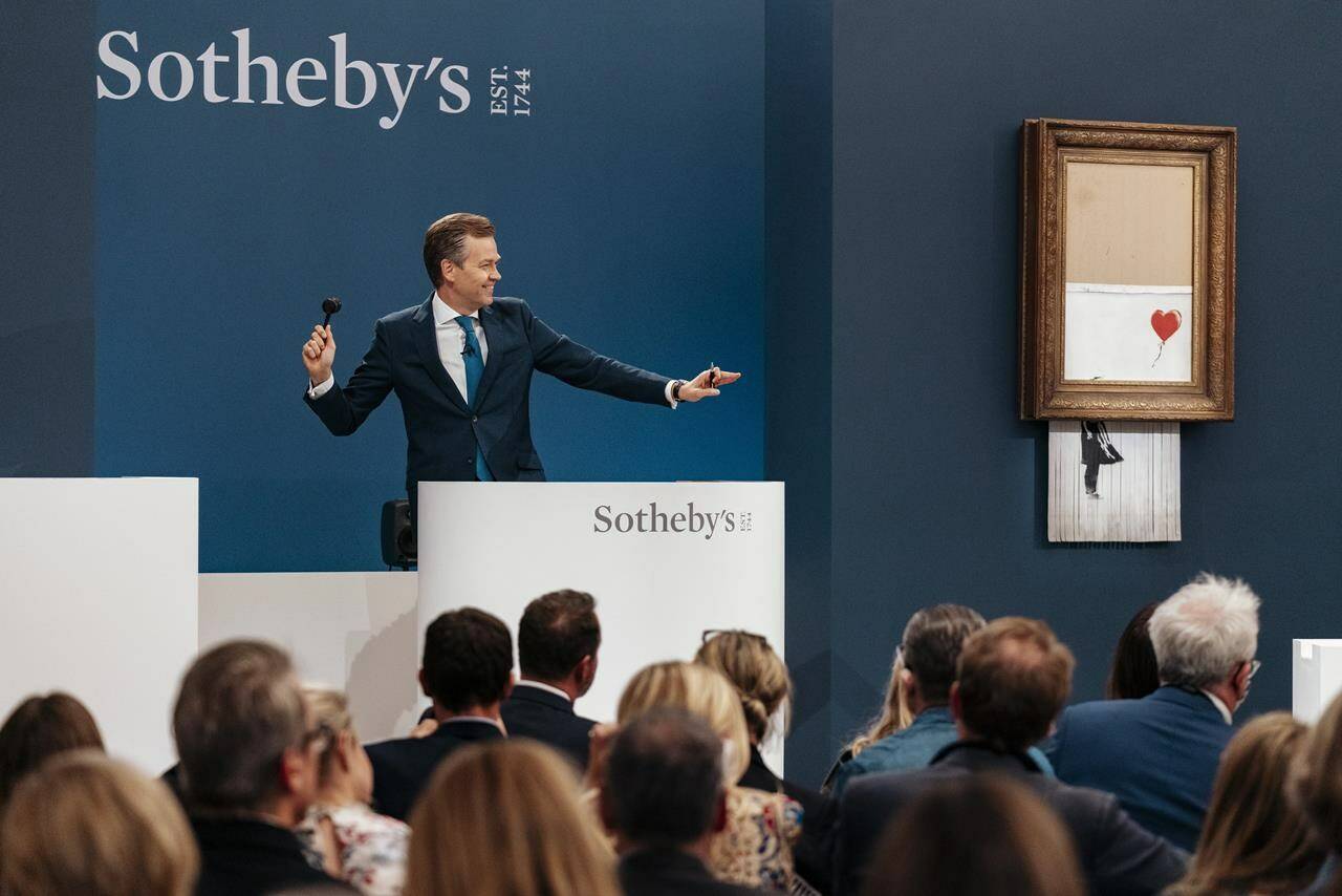 In this handout photo provided by Sotheby's Auction House, the auction for Banksy's "Love is the Bin" takes place in London, Thursday, Oct. 14, 2021. A work by British street artist Banksy that sensationally self-shredded just after it sold for $1.4 million has sold again for $25.4 million at an auction on Thursday. “Love is in the Bin” was offered by Sotheby’s in London, with a presale estimate of $5.5 million to $8.2 million. (Haydon Perrior/Sotheby's Auction House via AP)