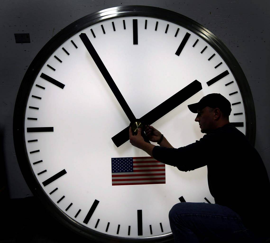Dave LeMote uses an allen wrench to adjust hands on a stainless steel tower clock at Electric Time Company, Inc. in Medfield, Mass., in this March 7, 2014 file photo. It’s that time of year where Canadians have the chance to catch up on some sleep as the clocks move back an hour Sunday, but an Ontario politician is optimistic it could be the last for the country’s most populous province. THE CANADIAN PRESS/AP-Elise Amendola