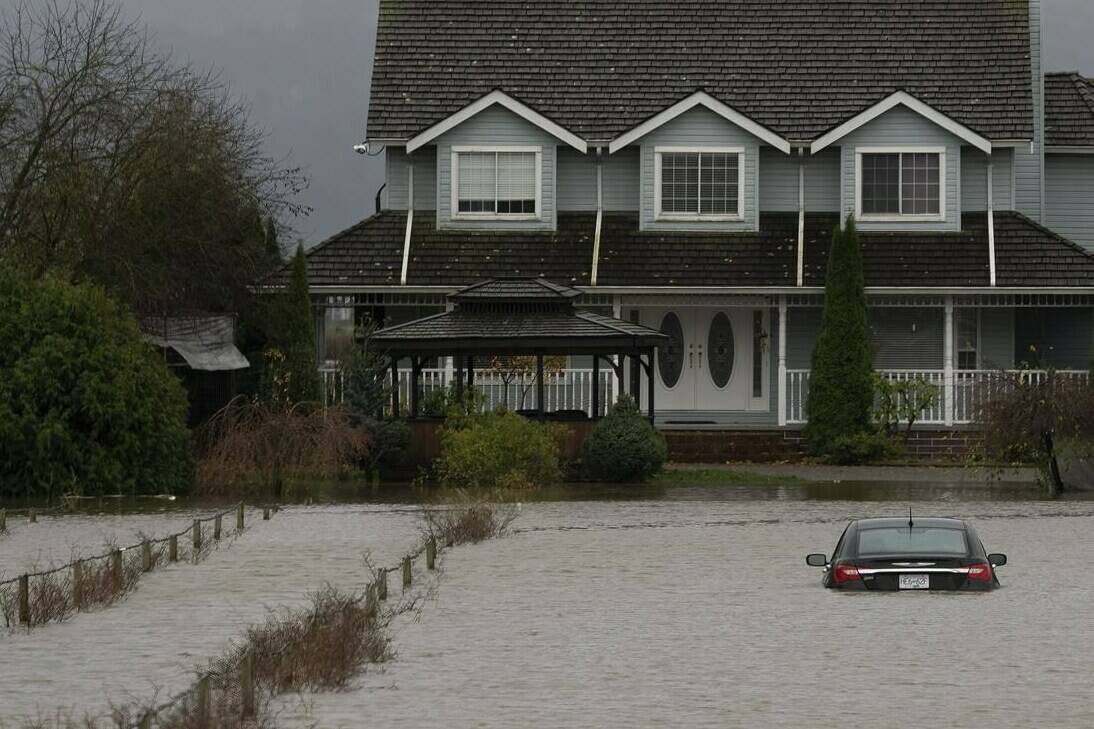 A vehicle is submerged in flood waters along a road in Abbotsford, B.C., Monday, Nov. 15, 2021. THE CANADIAN PRESS/Jonathan Hayward