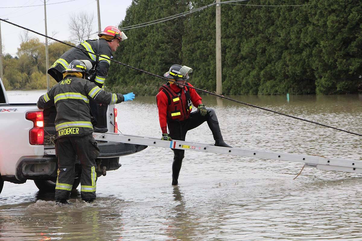 A member of Abbotsford Fire Rescue Service climbs on the ladder to walk towards the man to help him. (Vikki Hopes/Abbotsford News)