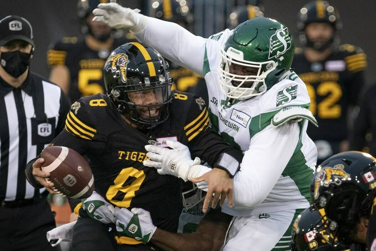 According to a Research Co. survey, 52 per cent of Canadians surveyed will skip the Grey Cup between the Hamilton Tiger-Cats and Winnipeg Blue Bombers Dec. 12. Pictured here, Ti-Cats QB Jeremiah Masoli (8) tries to elude Saskatchewan Roughriders’ DB Rolan Milligan (32) and DL Charbel Dabire (98) on Nov. 20. (THE CANADIAN PRESS/Peter Power)