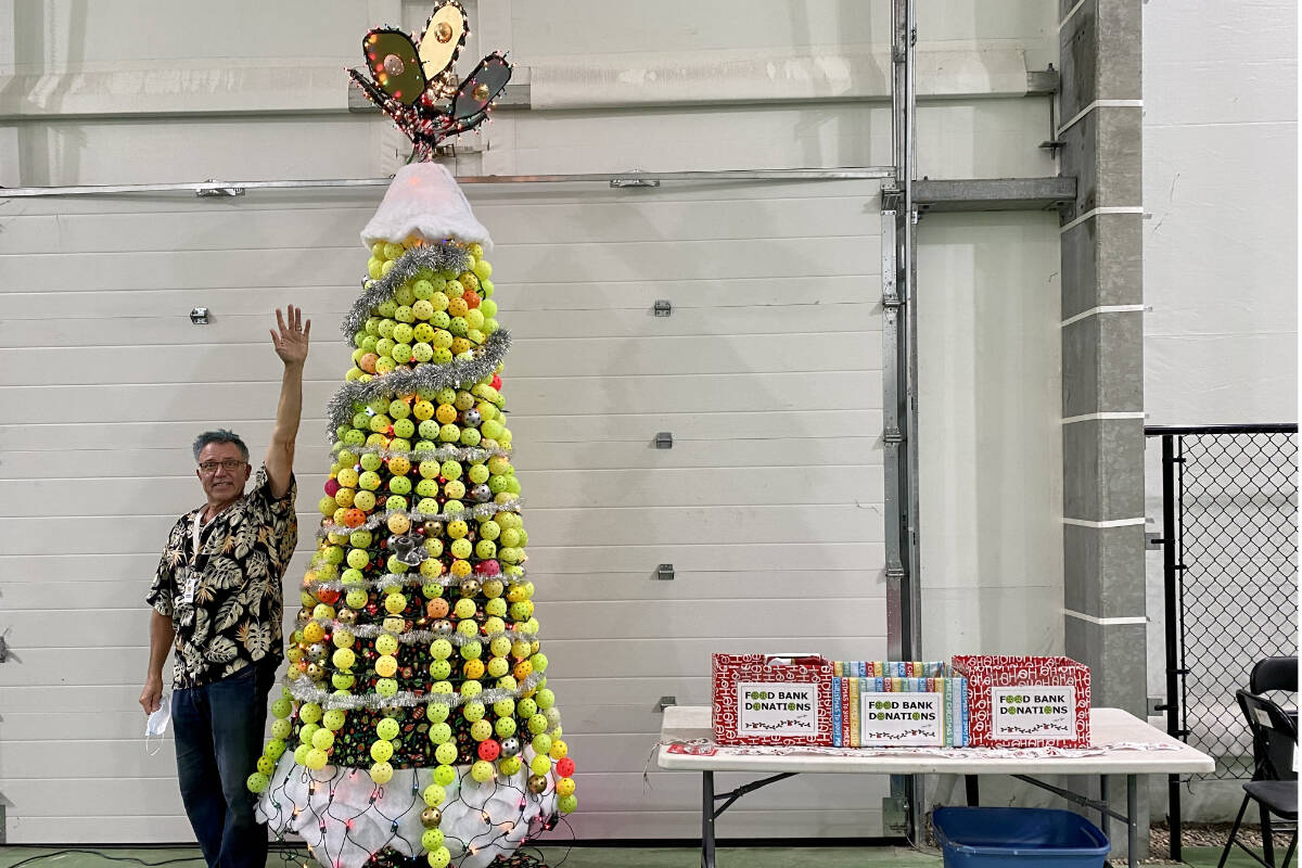 Marco Longley from the Vernon Pickleball Association is dwarfed by the 12-foot pickleball Christmas tree he created with 350 broken pickleballs that now adorns the Okanagan Wealth Advisors Pickleball Complex on Okanagan Landing Road. (Anne Longley photo)