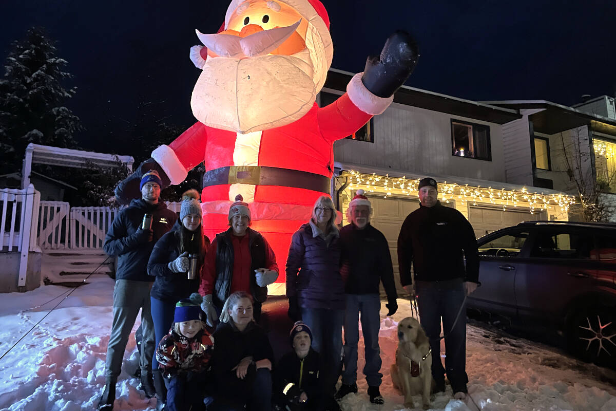 (Back row, L-R) Grand Forks’ Travis Tysick, wife Rena Bronstein, neighbours Karren Turner, Shirley and Ross Munro and Shane Zorn gather in front of a giant Santa on Valley Heights Drive Tuesday evening, Dec. 7. In the front row (L-R) are Cameron, Shannon and Blake Zorn and the Zorns’ dog, Marty. Photo: Laurie Tritschler