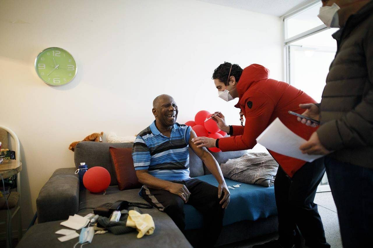 Dr. Nathan Stall administers a third dose of the COVID-19 vaccine to 77-year-old Vernal Davis as Dr. Stall and Toronto city councilor Josh Matlow bring third doses of the COVID-19 vaccine to homebound seniors and their caregivers in Toronto, Friday, Jan. 7, 2022. The pair are working against lowering the barriers to getting the most vulnerable boosted with their third dose. As parts of Canada see staggering rises in COVID-19 activity amid Omicron’s rapid spread, experts say the highly transmissible variant is training a spotlight on social inequities across the country. THE CANADIAN PRESS/Cole Burston