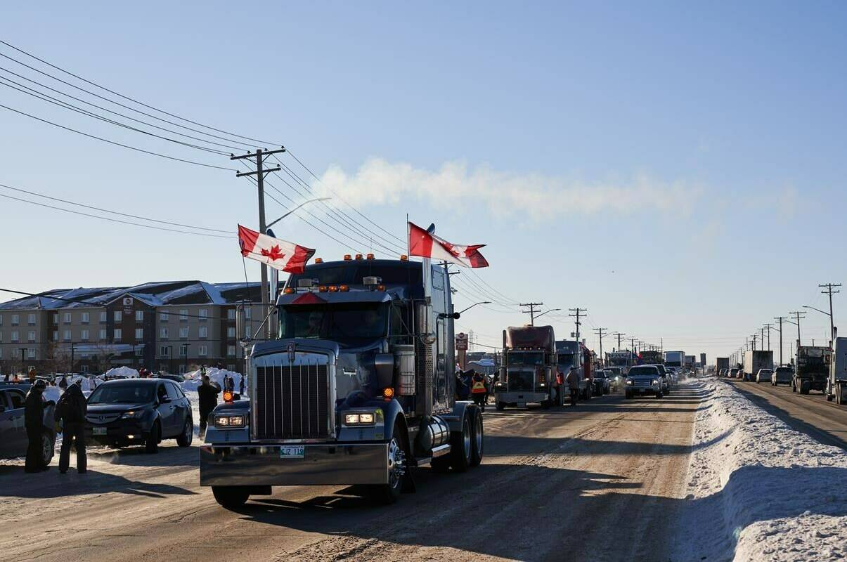 Protesters of COVID-19 restrictions, and supporters of Canadian truck drivers protesting the COVID-19 vaccine mandate cheer on a convoy of trucks on their way to Ottawa, on the Trans-Canada Highway west of Winnipeg, Man., Tuesday January 25, 2022. THE CANADIAN PRESS/David Lipnowski