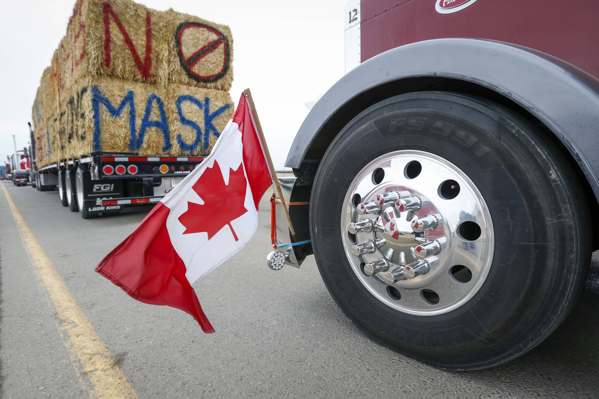 The Canadian flag is reflected in a wheel hub as anti-mandate demonstrators gather as a truck convoy blocks the highway the busy U.S. border crossing in Coutts, Alta., Monday, Jan. 31, 2022.THE CANADIAN PRESS/Jeff McIntosh