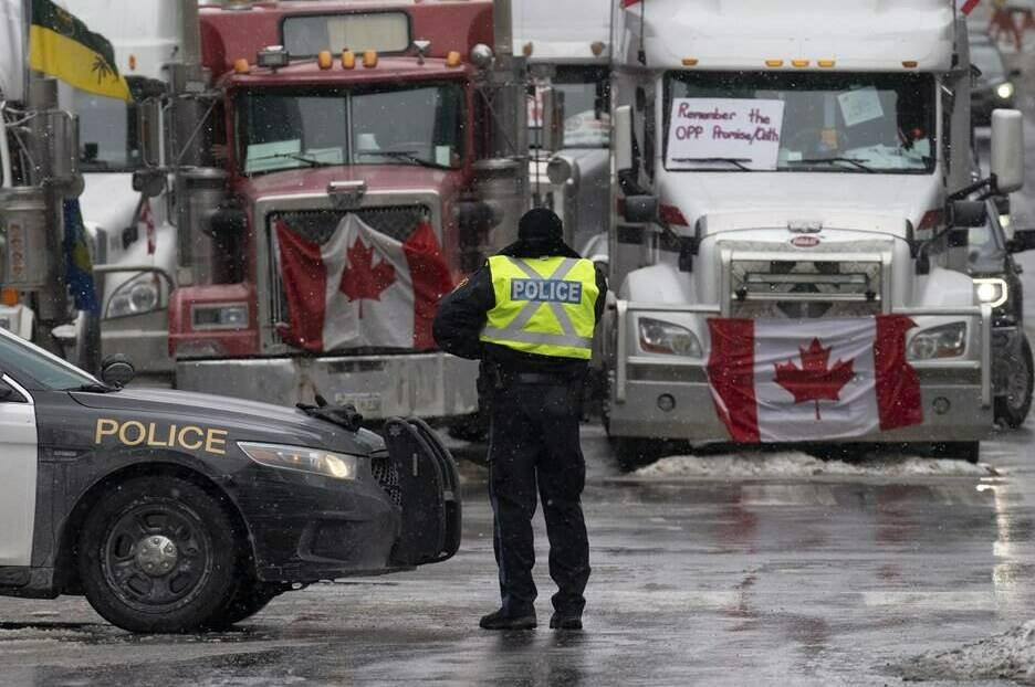 Police at a barricade in front of vehicles parked as part of the trucker protest, Tuesday, Feb. 8, 2022, in Ottawa’s downtown core. THE CANADIAN PRESS/Adrian Wyld