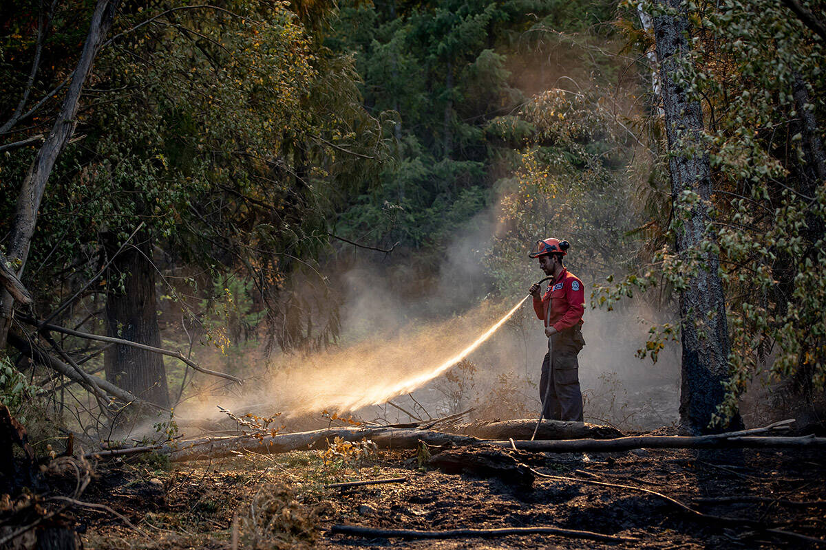 Wildland firefighter Sasha Terhoch sprays water on hot spots remaining from a controlled burn the B.C. Wildfire Service conducted to help contain the White Rock Lake wildfire on Okanagan Indian Band land, northwest of Vernon, B.C., on Wednesday, August 25, 2021. THE CANADIAN PRESS/Darryl Dyck