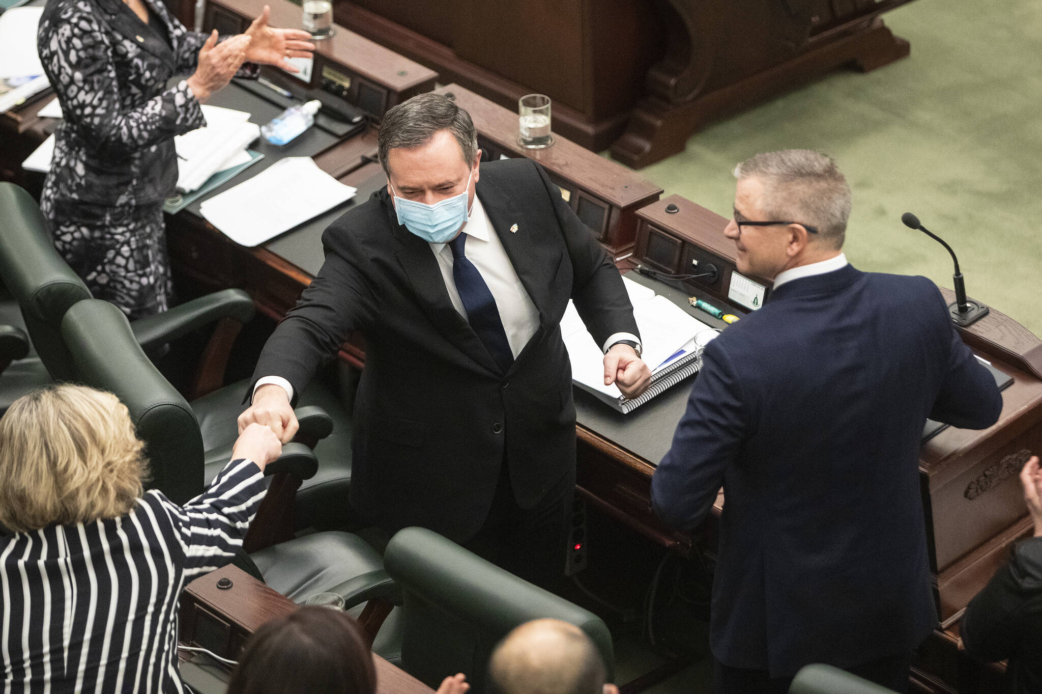 Alberta Premier Jason Kenney fist bumps an MLA after Finance Minister Travis Toews delivered the 2022 budget in Edmonton on Thursday February 24, 2022. THE CANADIAN PRESS/Jason Franson