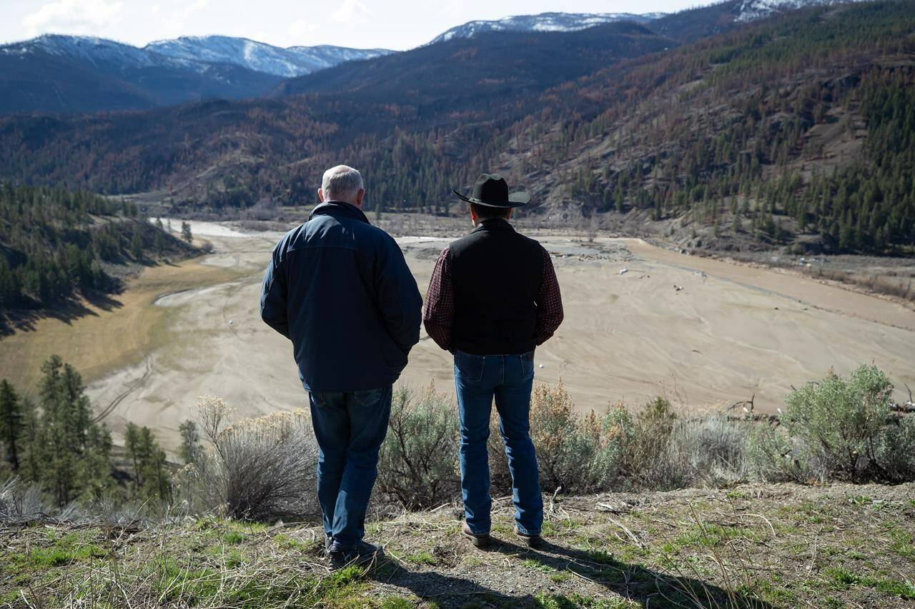 B.C. Minister of Public Safety and Solicitor General Mike Farnworth, left, and Shackan Indian Band Chief Arnie Lampreau (Swakum) view damage to Shackan land caused by last summer’s wildfires and November’s flooding west of Merritt, B.C., on Thursday, March 24, 2022. THE CANADIAN PRESS/Darryl Dyck