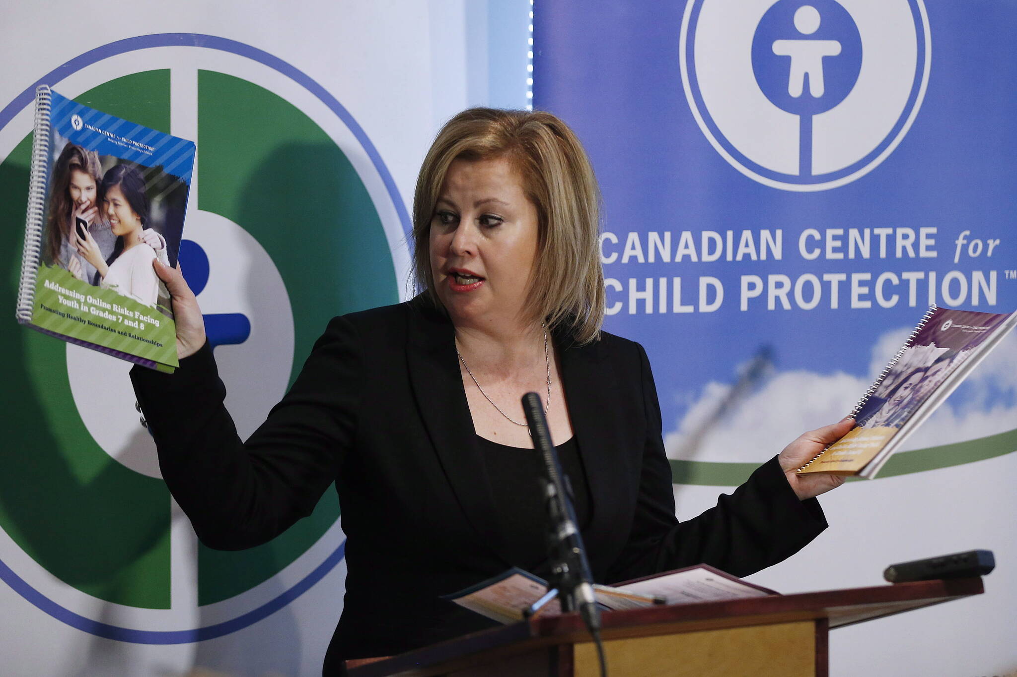 Lianna McDonald, Executive Director of the Canadian Centre for Child Protection, holds text books as she speaks at a press conference at the Canadian Centre for Child Protection in Winnipeg Wednesday, October 1, 2014. THE CANADIAN PRESS/John Woods