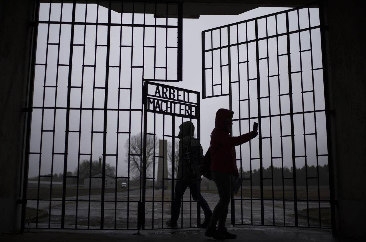 People take photos as they enter the Sachsenhausen Nazi death camp through the gate with the phrase ‘Arbeit macht frei’ (work sets you free), in Oranienburg, about 30 kilometres north of Berlin, Tuesday, Jan. 25, 2022. The Federal government is to use a bill enacting the budget to change the Criminal Code this year, building on existing laws outlawing the incitement of hatred. THE CANADIAN PRESS/AP-Markus Schreiber