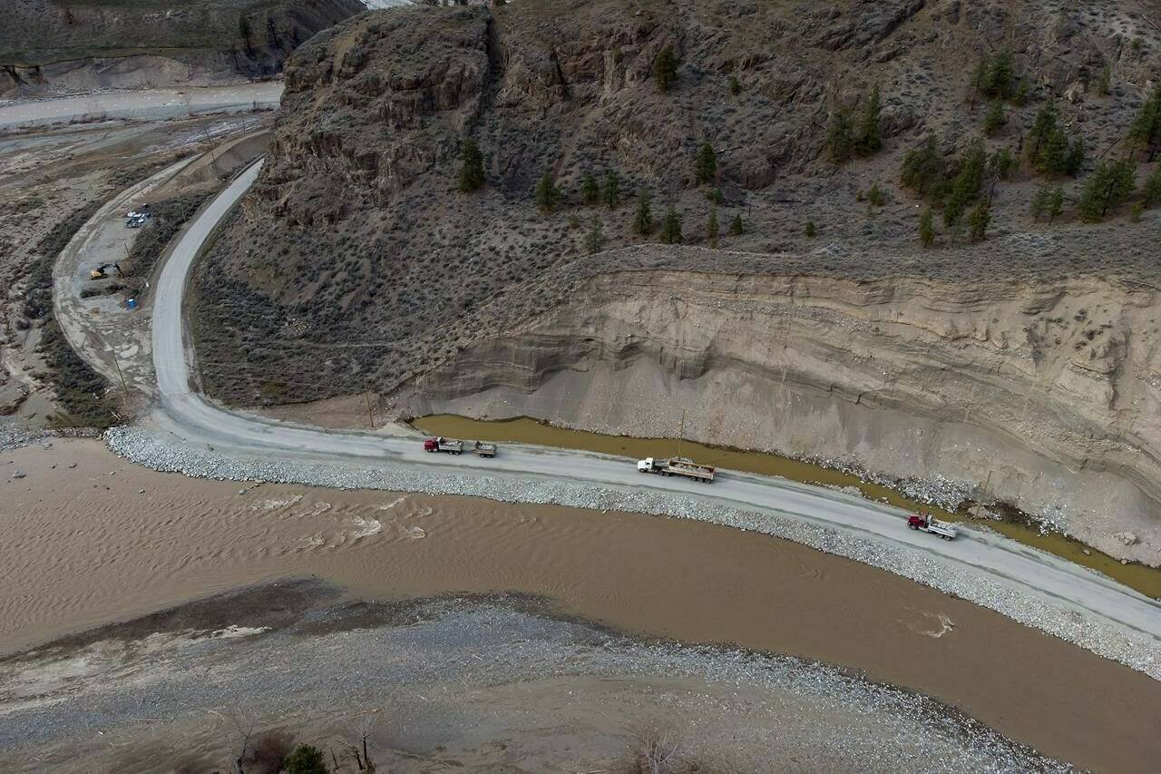 Trucks haul loads of rock on a section of Highway 8 along the Nicola River that had to be rebuilt after it was washed away during November flooding on the Shackan Indian Band, northwest of Merritt, B.C., on Thursday, March 24, 2022. Major wildfires, droughts and mudslides last year dramatically altered the landscape, raising questions about the river’s ability to handle the spring thaw. THE CANADIAN PRESS/Darryl Dyck
