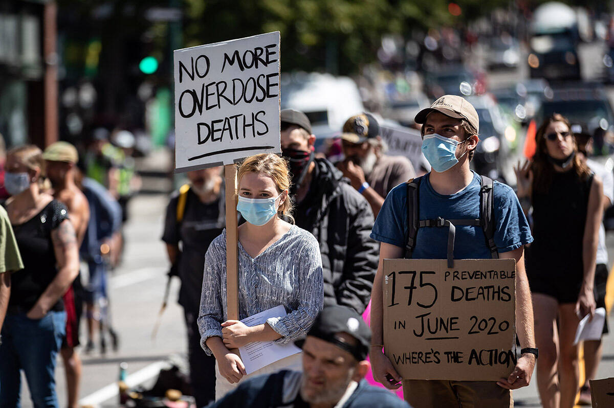 People hold signs during a memorial march to remember victims of overdose deaths in Vancouver in 2020. In March 2022, 165 people died of toxic drug poisoning in B.C. THE CANADIAN PRESS/Darryl Dyck