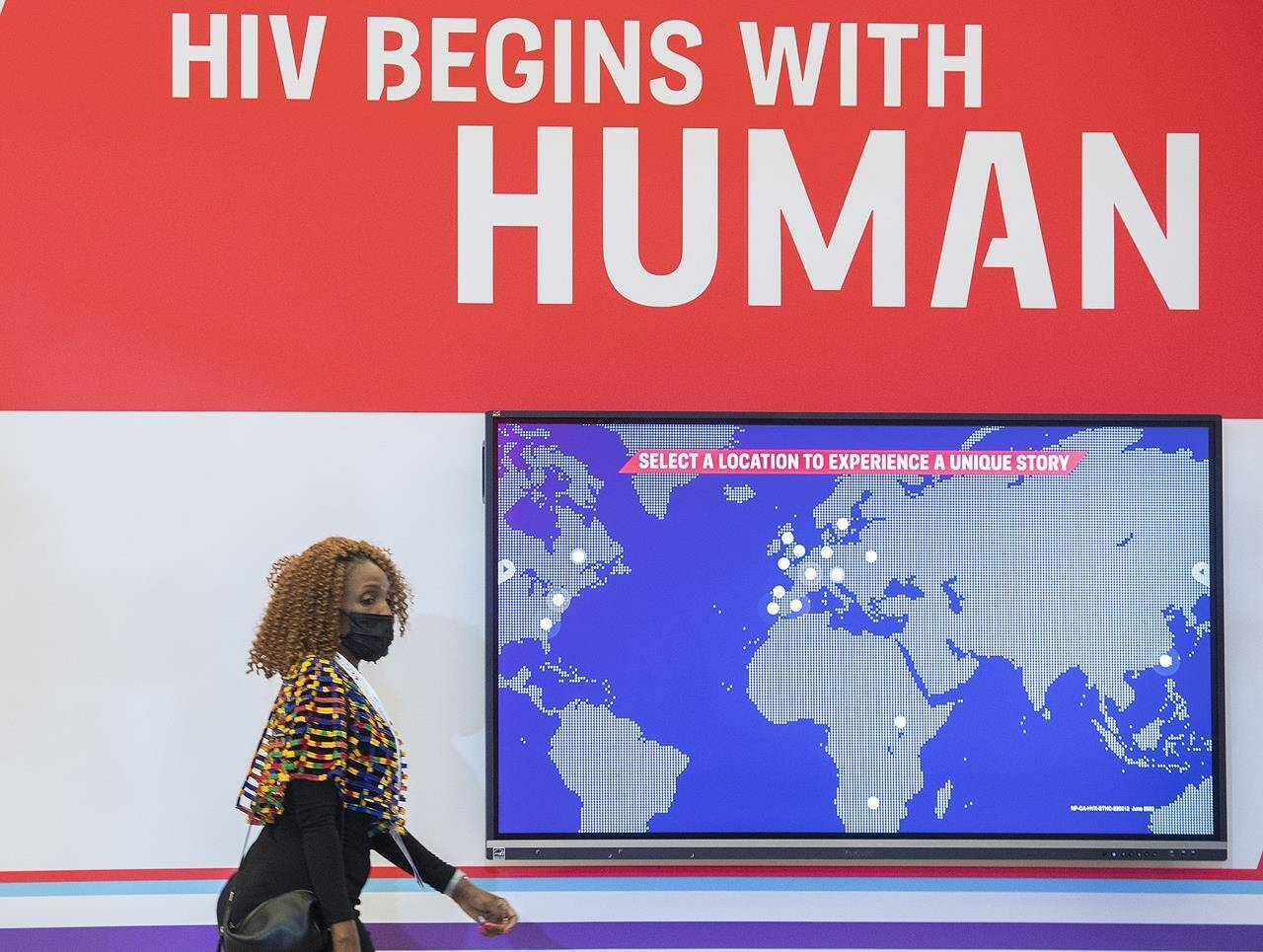 A woman walks by a sign during the AIDS 2022 conference in Montreal, Sunday, July 31, 2022. THE CANADIAN PRESS/Graham Hughes