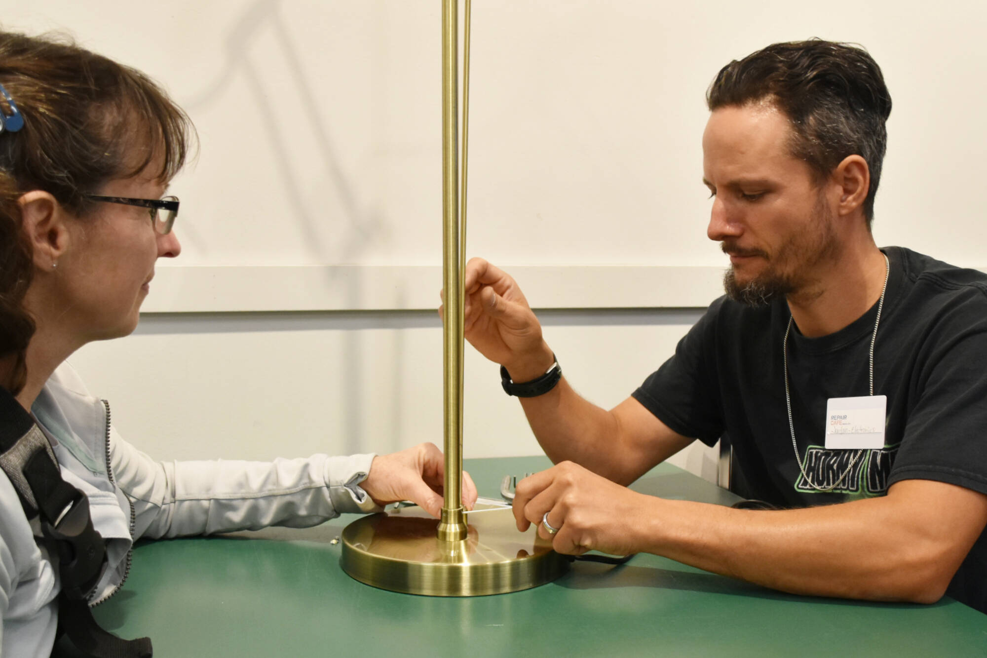 Electronics specialist Jordan Adair finishes fixing a lamp for Cathy MacArthur at the Repair Cafe held in Salmon Arm on Saturday, Aug. 27. Adair said he was surprised by how busy it was. (Martha Wickett - Salmon Arm Observer)