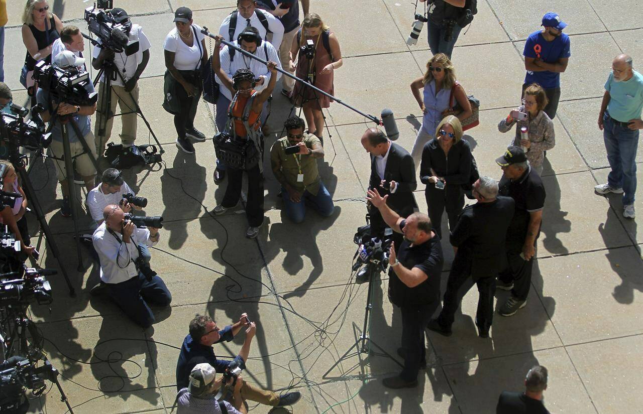 Alex Jones, bottom right, speaks to the media outside the courthouse after Jones’ Sandy Hook defamation damages trial at Connecticut Superior Court in Waterbury, Conn., Wednesday, Sept. 21, 2022. (Christian Abraham/Hearst Connecticut Media via AP)
