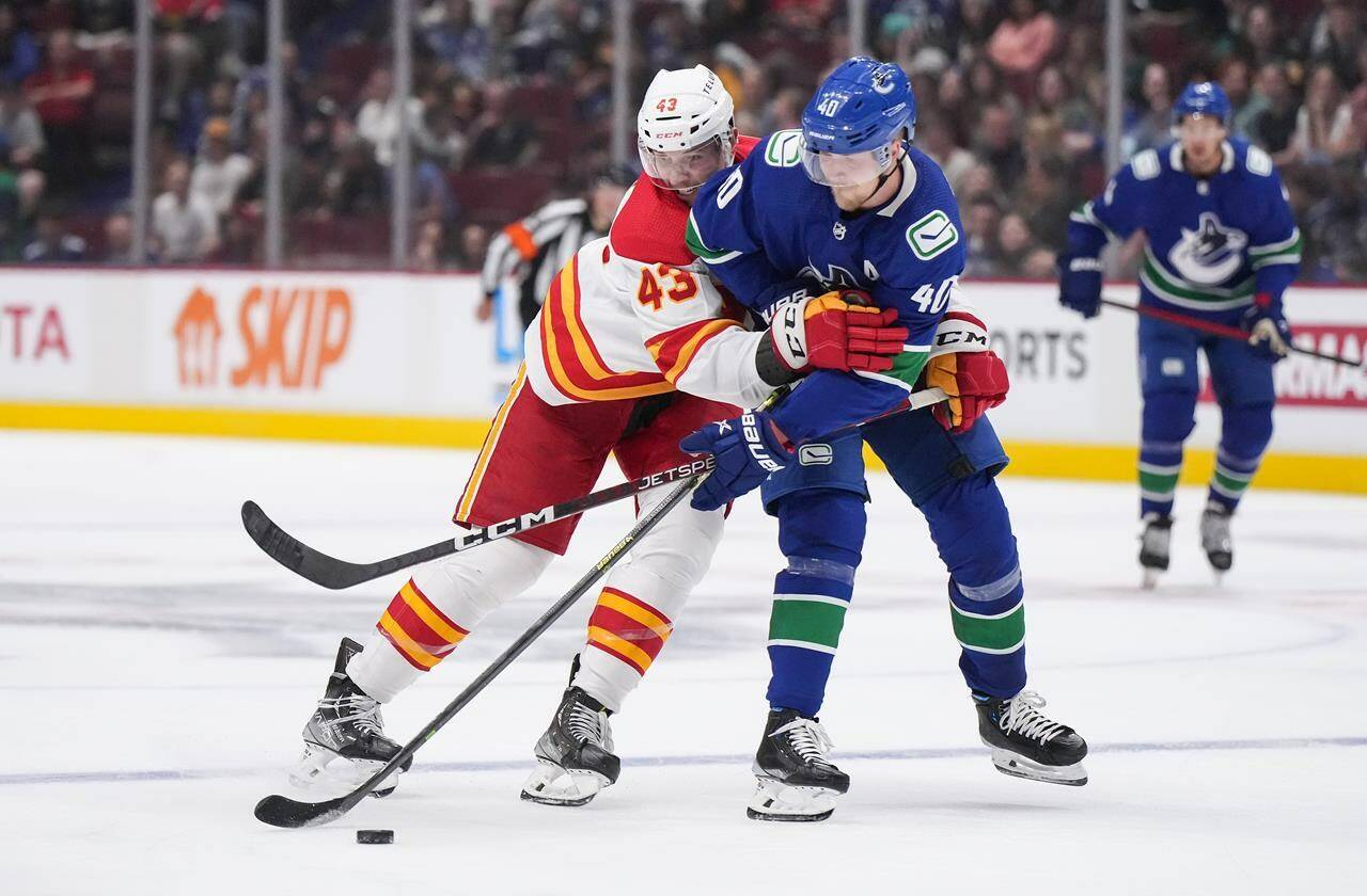 Calgary Flames’ Adam Klapka, left, of the Czech Republic, ties up Vancouver Canucks’ Elias Petterson, of Sweden, during the second period of a pre-season NHL hockey game in Vancouver, B.C., Sunday, Sept. 25, 2022. THE CANADIAN PRESS/Darryl Dyck