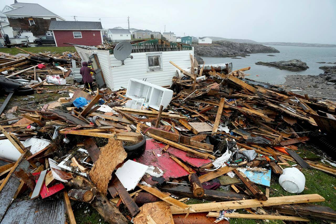 A resident and search and rescue worker examine the destroyed remains of a home in Port aux Basques, N.L., Monday, Sept.26, 2022. Post-tropical storm Fiona carved a path of devastation across parts of Atlantic Canada, leaving behind smashed homes, roads strewn with debris and hundreds of thousands of people without power. THE CANADIAN PRESS/Frank Gunn