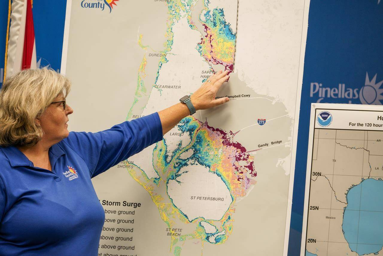FILE - Emergency Management Director Cathie Perkins references a map indicating where storm surge would impact the county, urging anyone living in those areas to evacuate, during a press conference regarding Hurricane Ian at the Pinellas County Emergency Operations Center, Sept. 26, 2022, in Largo, Fla. Hurricane Ian is quickly gaining monstrous strength as it moves over oceans partly heated up by climate change. (Martha Asencio-Rhine/Tampa Bay Times via AP, File)