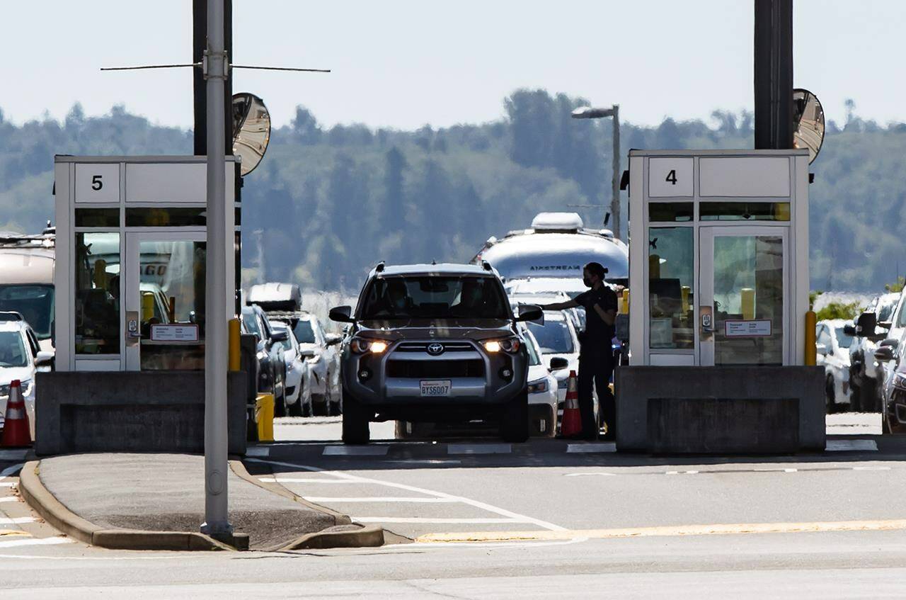 A Canada Border Services Agency officer hands documents back to a motorist entering Canada at the Douglas-Peace Arch border crossing, in Surrey, B.C., on Monday, Aug. 9, 2021. The head of a union representing Canada’s customs and immigration officers says chronic staffing shortages mean long waits at the border won’t necessarily disappear when use of the ArriveCan app soon becomes optional. THE CANADIAN PRESS/Darryl Dyck