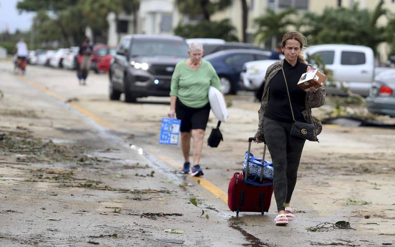 King Point residents leave with their belongings after an apparent overnight tornado spawned from Hurricane Ian at Kings Point 55+ community in Delray Beach, Fla., on Wednesday, Sept. 28, 2022. (Carline Jean /South Florida Sun-Sentinel via AP)