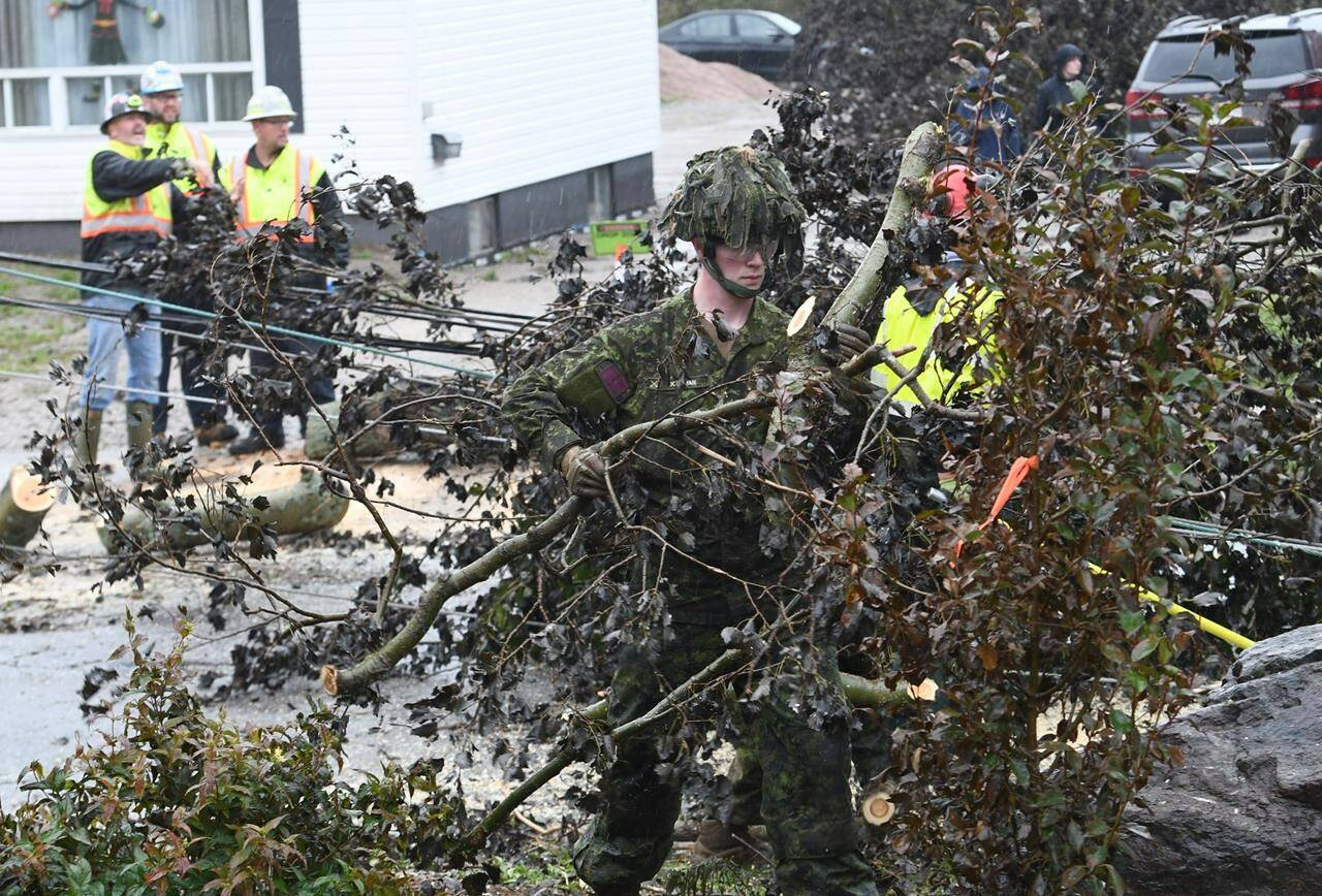 Cpl. Owen Donovan of the Cape Breton Highlanders removes brush under the direction of Nova Scotia Power officials along Steeles Hill Road in Glace Bay, N.S., Monday, Sept. 26, 2022. Defence Minister Anita Anand says there are now 700 military members in Atlantic Canada helping with the cleanup after post-tropical storm Fiona left much of the region in tatters. THE CANADIAN PRESS/Vaughan Merchant