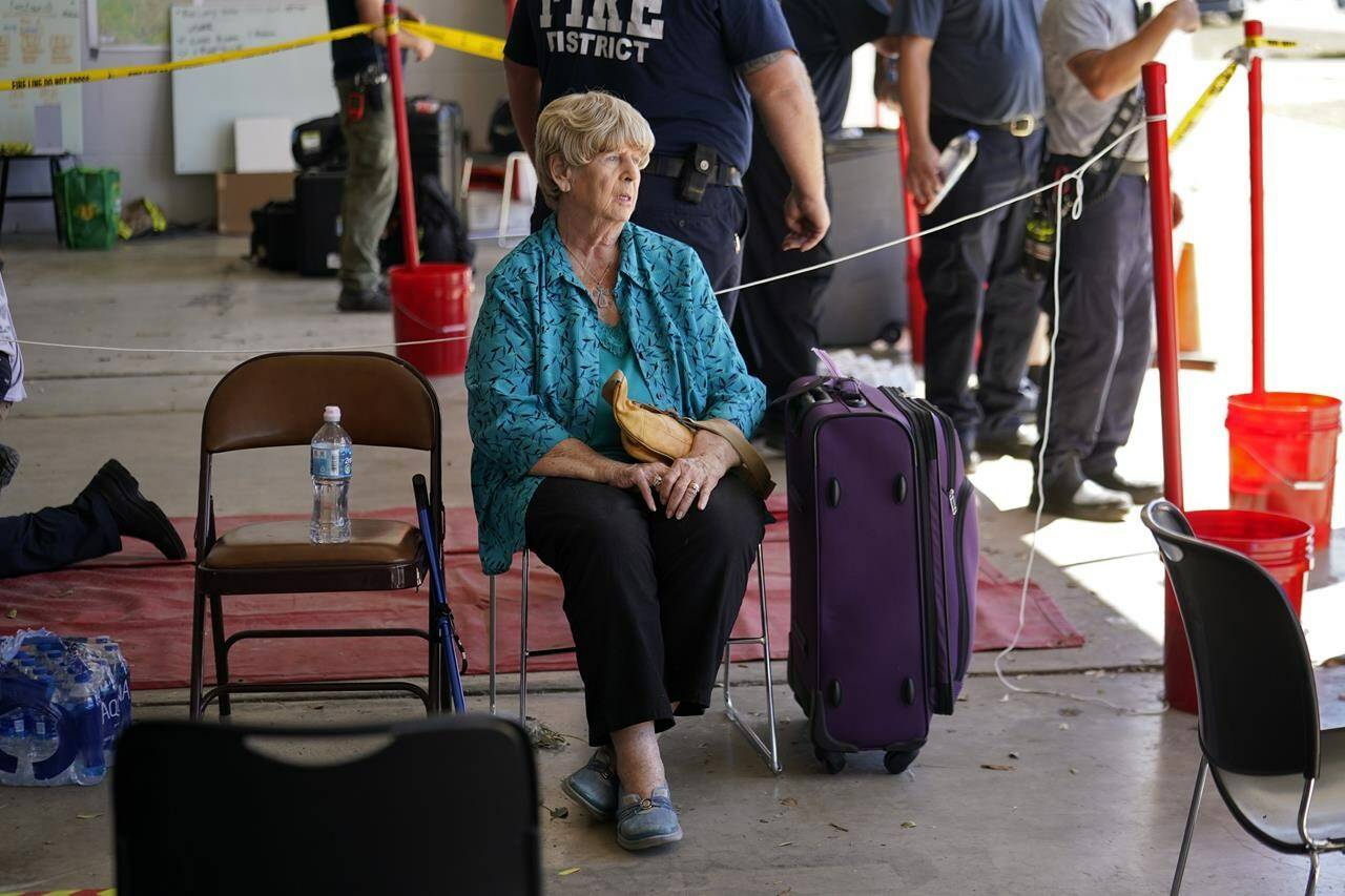 Linda Newman, a resident of Pine Island who rode out the storm on the island and recently lost her husband, waits to be evacuated in the aftermath of Hurricane Ian on Pine Island in Lee County, Fla., Sunday, Oct. 2, 2022. The only bridge to the island is heavily damaged so it can only be reached by boat or air. (AP Photo/Gerald Herbert)
