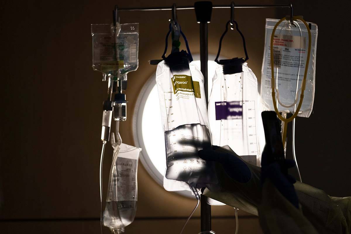 FILE - A nurse checks on IV fluids while talking to a COVID-19 patient at a Los Angeles medical centre on Dec. 13, 2021. Richmond, B.C. nurse Xiaofang (Sophie) Huang was handed a two-week suspension in September 2022 for a series of issues, including failing to monitor IV infusions. (AP Photo/Jae C. Hong)