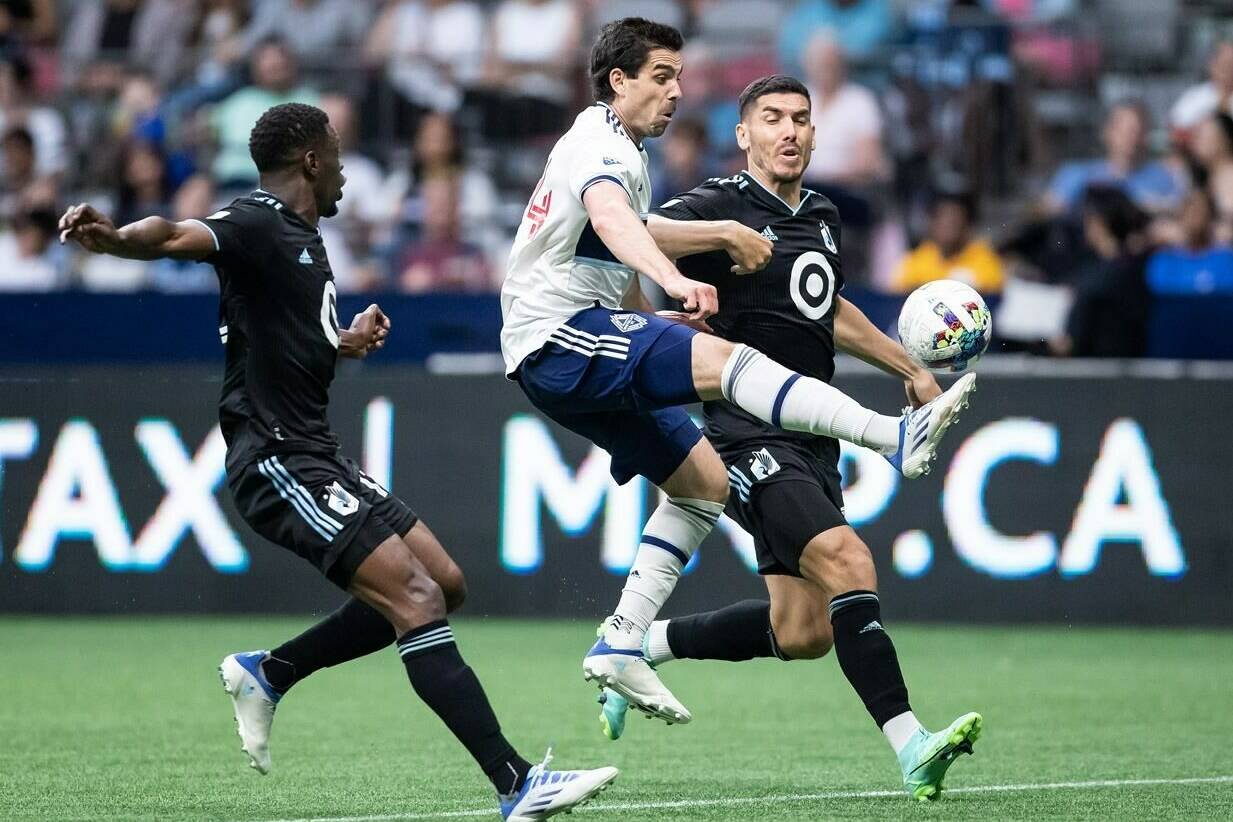 Vancouver Whitecaps’ Brian White, centre, receives a pass between Minnesota United’s Bakaye Dibassy, left, and Michael Boxall during the second half of an MLS soccer game in Vancouver, B.C., Friday, July 8, 2022. THE CANADIAN PRESS/Darryl Dyck