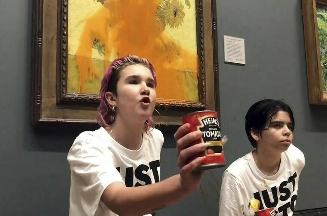 Handout photo issued by Just Stop Oil of two protesters who have thrown tinned soup at Vincent Van Gogh’s famous 1888 work Sunflowers at the National Gallery in London, Friday Oct. 14, 2022. The group Just Stop Oil, which wants the British government to halt new oil and gas projects, said activists dumped two cans of Heinz tomato soup over the oil painting on Friday. London’s Metropolitan Police said officers arrested two people on suspicion of criminal damage and aggravated trespass. (Just Stop Oil via AP)