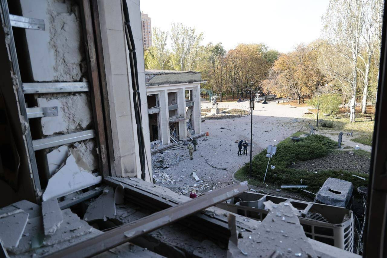 Investigators are seen through a broken window as they work at the site of the damaged administrative building after shelling in Donetsk, the capital of Donetsk People’s Republic, eastern Ukraine, Sunday, Oct. 16, 2022. Russian media reports say the mayor’s office in a key eastern Ukrainian city controlled by pro-Kremlin separatists has been struck by rockets. There were no immediate reports of casualties in the Sunday morning attack. (AP Photo/Alexei Alexandrov)