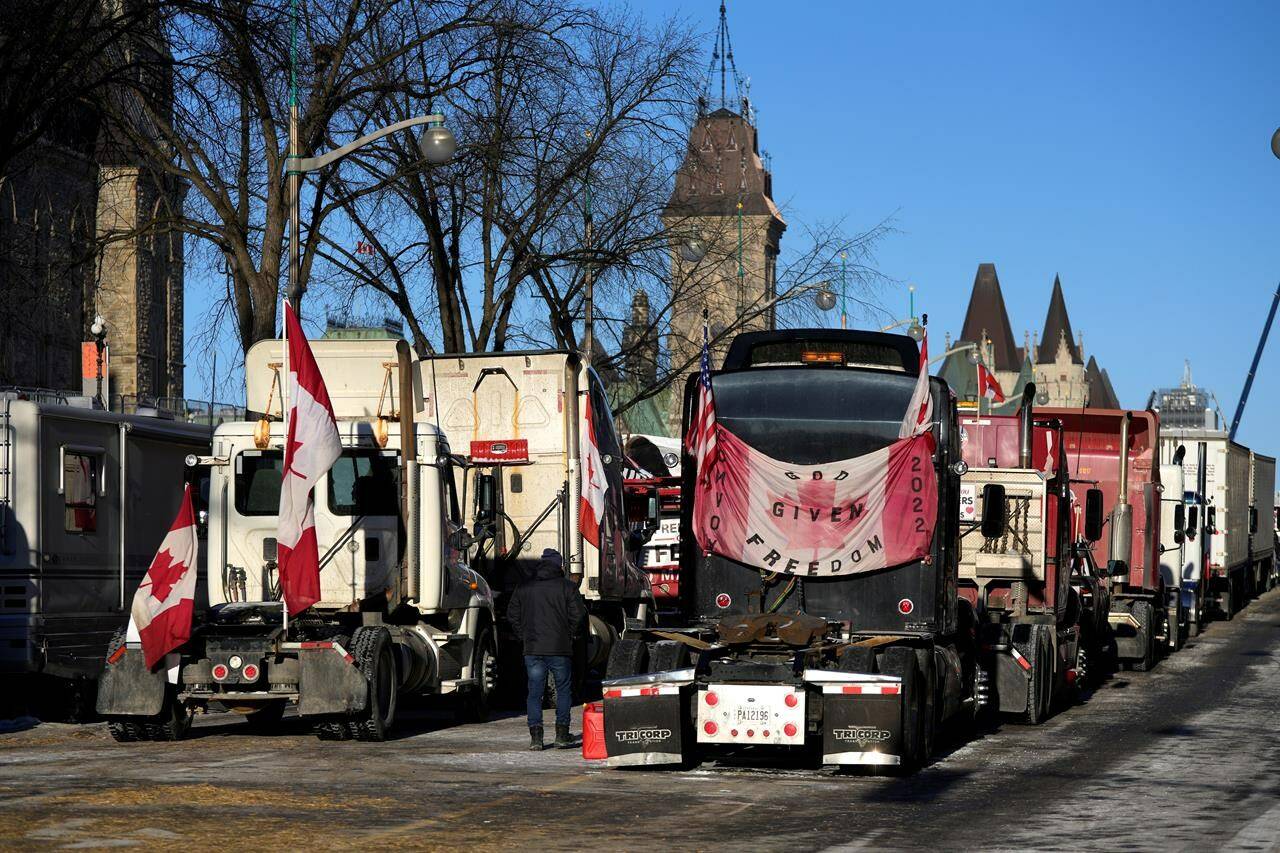 A person walks among trucks on Wellington Street on the 18th day of a protest against COVID-19 measures that has grown into a broader anti-government protest, in Ottawa, on Monday, Feb. 14, 2022. THE CANADIAN PRESS/Justin Tang