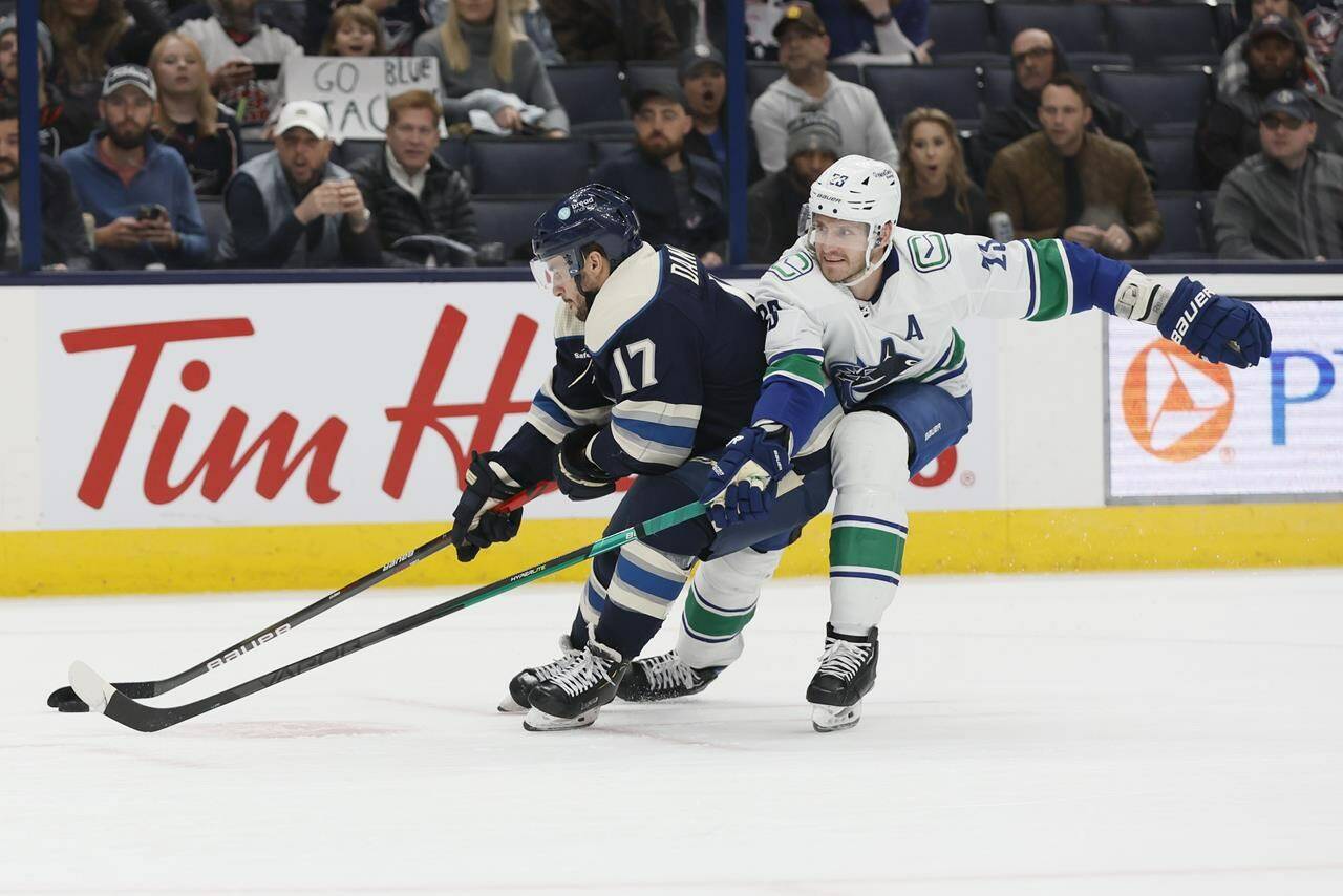 Columbus Blue Jackets’ Justin Danforth, left, keeps the puck away from Vancouver Canucks’ Oliver Ekman-Larsson during the second period of an NHL hockey game Tuesday, Oct. 18, 2022, in Columbus, Ohio. (AP Photo/Jay LaPrete)