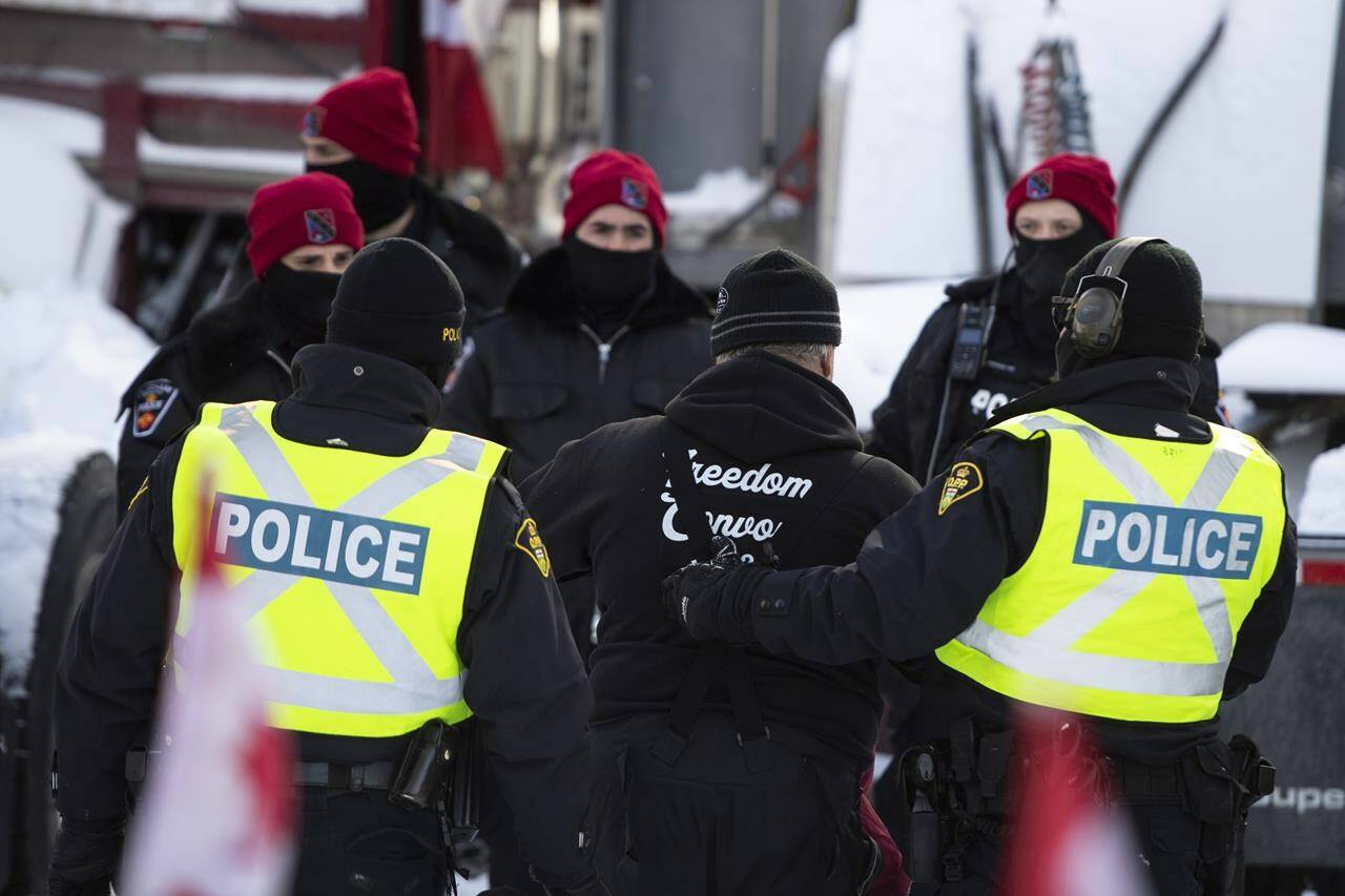 A trucker is led away after leaving his truck as police aim to end an ongoing protest against COVID-19 measures that has grown into a broader anti-government protest, on its 22nd day, in Ottawa, on Friday, Feb. 18, 2022. A former senior Ontario Provincial Police officer says early meetings between Ottawa police officials and experts sent by other agencies to help were “unprofessional and disrespectful” during the “Freedom Convoy” protest. THE CANADIAN PRESS/Justin Tang