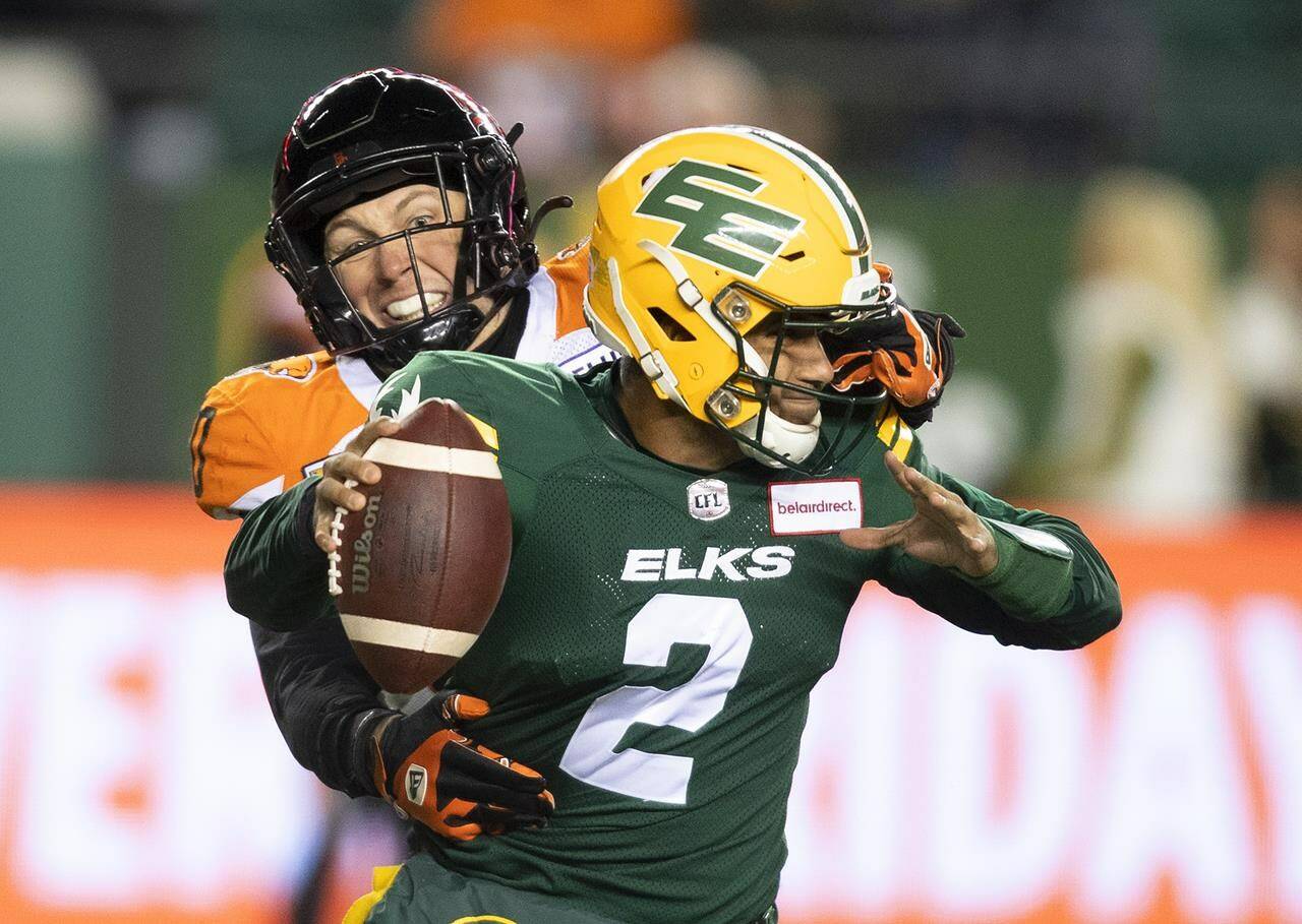 B.C. Lions’ Mathieu Betts (90) grabs the face mask of Edmonton Elks quarterback Tre Ford (2) during first half CFL action in Edmonton, Alta., on Friday October 21, 2022. THE CANADIAN PRESS/Jason Franson.