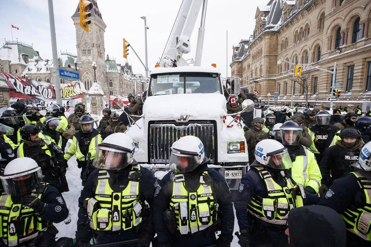 Police hang off a truck as authorities work to end a protest against COVID-19 measures that had grown into a broader anti-government demonstration and occupation lasting for weeks, in Ottawa, Saturday, Feb. 19, 2022. The head of Ontario Provincial Police is defending comments he made about the “Freedom Convoy” posing a threat to national security. THE CANADIAN PRESS/Cole Burston