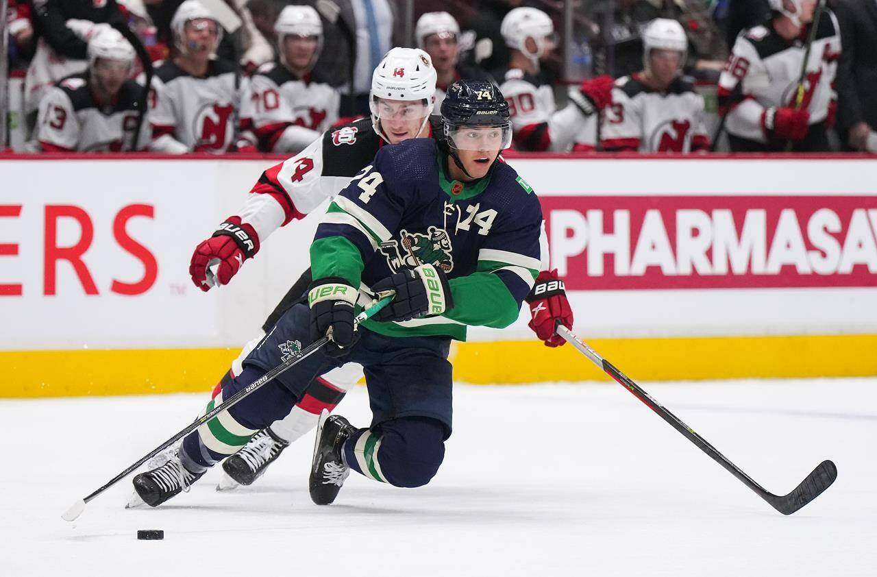 Vancouver Canucks’ Ethan Bear (74) skates with the puck in front of New Jersey Devils’ Nathan Bastian (14) during the second period of an NHL hockey game in Vancouver, B.C., Tuesday, Nov. 1, 2022. THE CANADIAN PRESS/Darryl Dyck