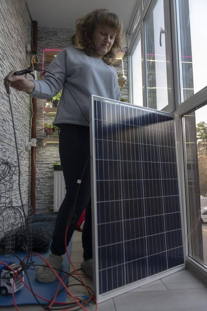 Kyiv resident Anna shows a solar panel that can provide energy for an entire apartment for 4 hours in Kyiv, Ukraine, Tuesday, Nov. 1, 2022. Due to Russian shelling of Ukrainian critical infrastructure facilities, Ukrainians are forced to come up with different methods to accumulate energy. (AP Photo/Andrew Kravchenko)