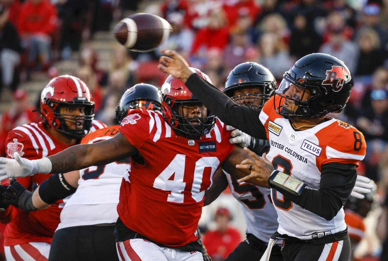 BC Lions quarterback Vernon Adams, right, throws the ball as Calgary Stampeders defensive lineman Shawn Lemon closes in during second half CFL football action in Calgary, Saturday, Sept. 17, 2022.THE CANADIAN PRESS/Jeff McIntosh