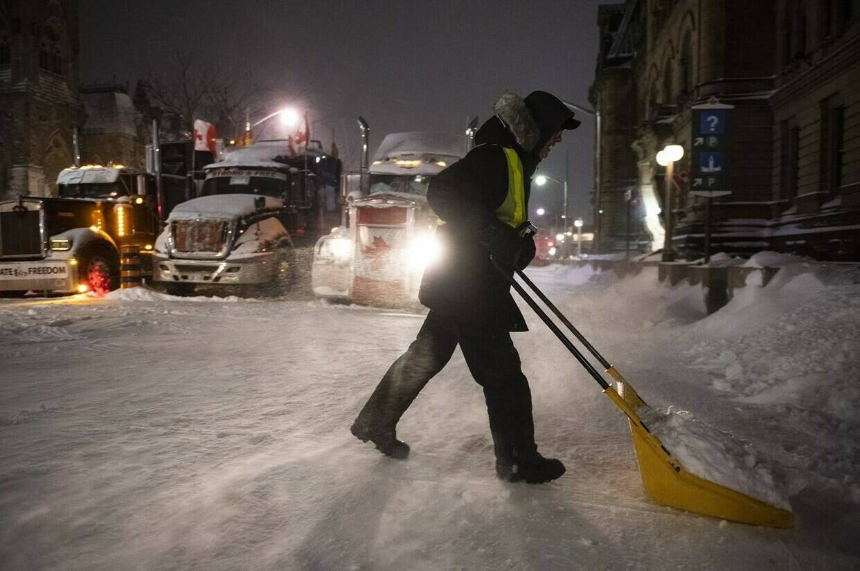 A protester shovels snow from Wellington Street in front of a blockade of trucks as a winter storm warning is in effect, on the 22nd day of a protest against COVID-19 measures that has grown into a broader anti-government protest, in Ottawa, on Friday, Feb. 18, 2022. The commission investigating the federal government's invocation of the Emergencies Act says most of the millions of dollars raised by the "Freedom Convoy" ended up in an escrow account or returned to donors. THE CANADIAN PRESS/Justin Tang