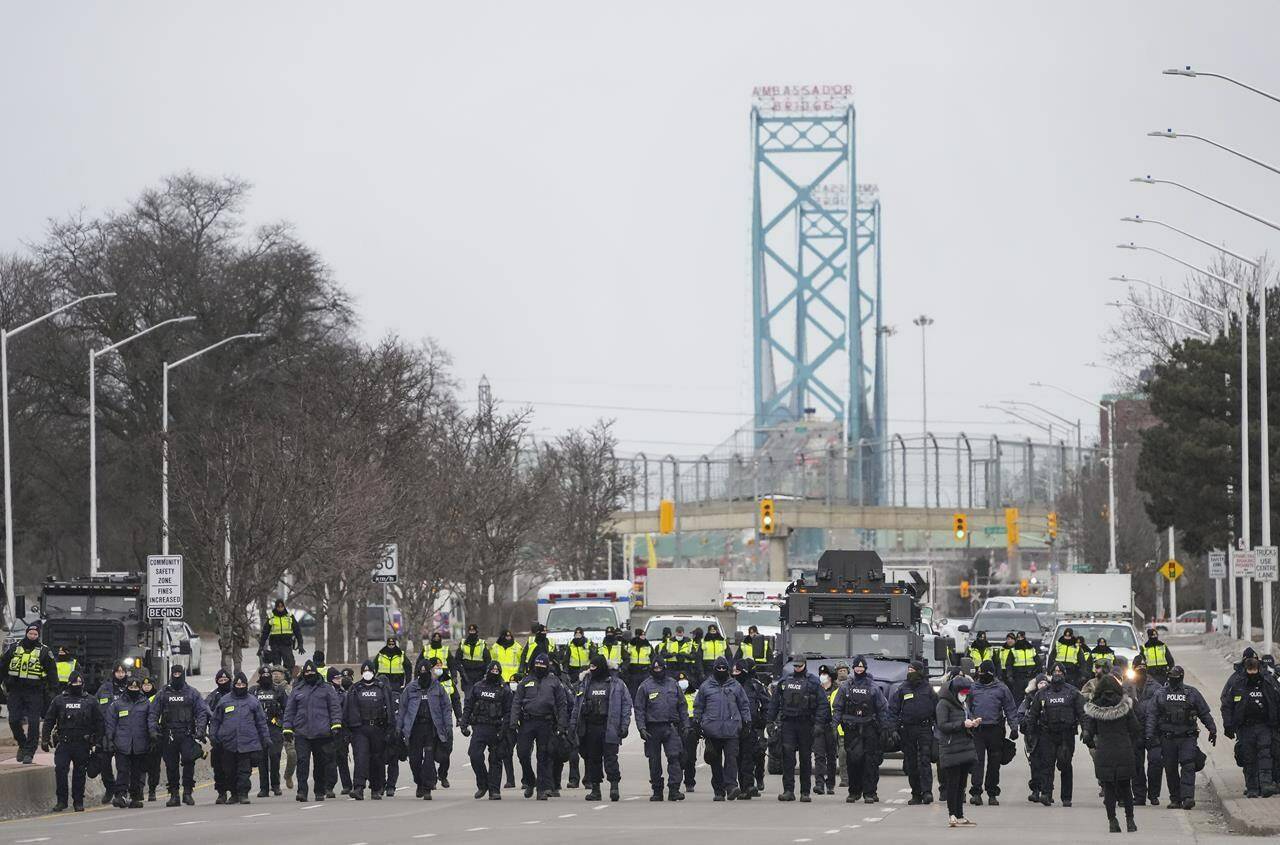 Police walk the line to remove all truckers and supporters in Windsor, Ont., Sunday, Feb. 13, 2022. THE CANADIAN PRESS/Nathan Denette