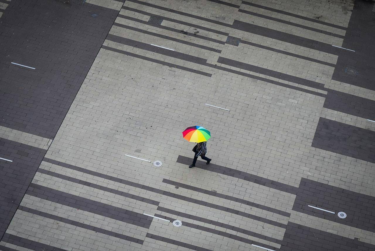 A pedestrian carries an umbrella as light rain falls in Surrey, B.C., on Friday, October 21, 2022. British Columbia’s Sunshine Coast Regional District says continued “uncertainty” about water supplies means it will seek an extension of the state of local emergency declared last month. THE CANADIAN PRESS/Darryl Dyck