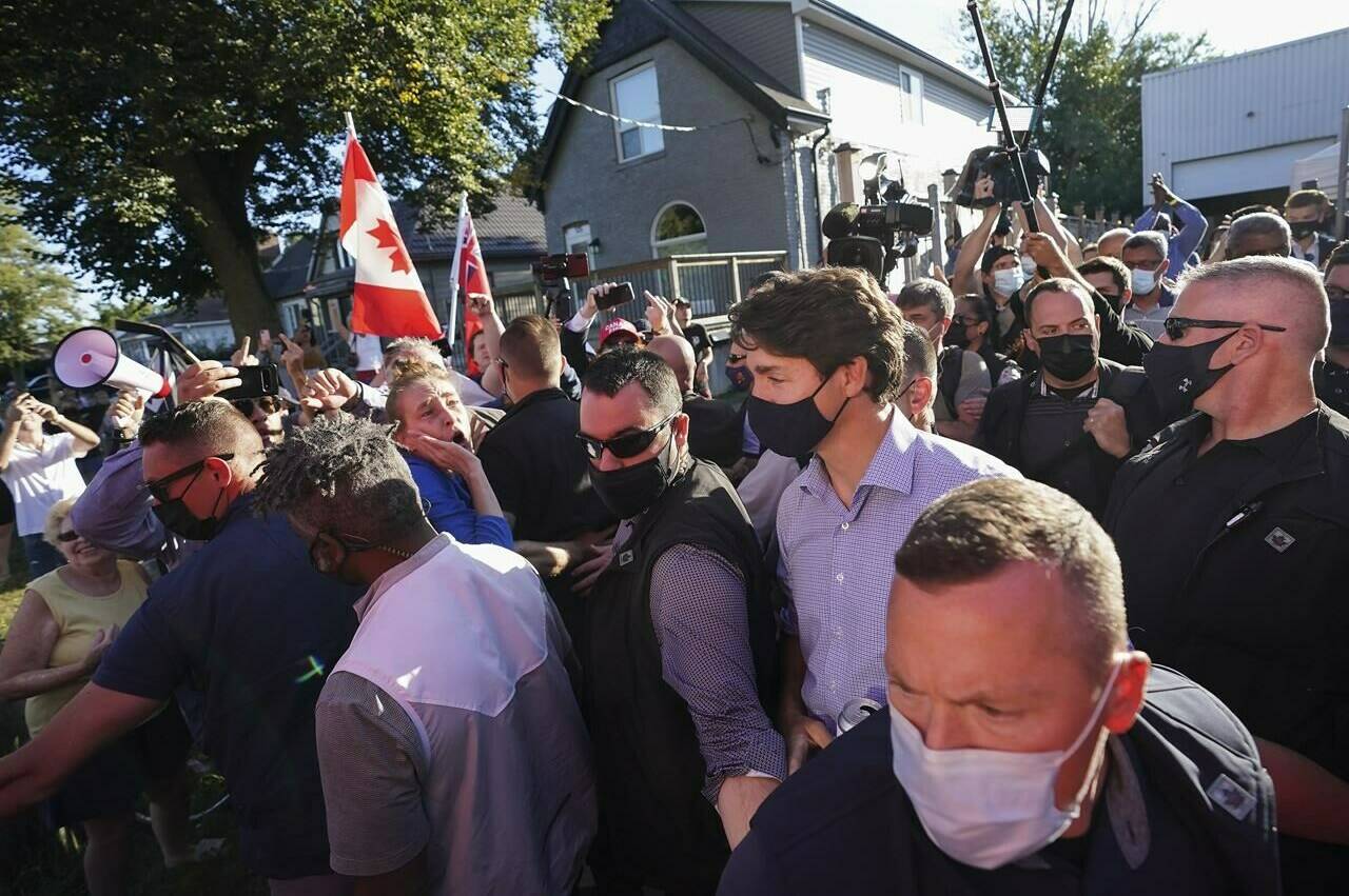 Liberal Leader Justin Trudeau is escorted by his RCMP security detail as protesters shout and throw rocks while leaving a campaign stop at a local micro brewery during the Canadian federal election campaign in London Ont., on Monday, September 6, 2021. THE CANADIAN PRESS/Nathan Denette