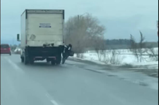 A man hanging from the back of a transport truck took a nasty fall on Highway 97 at the south end of Vernon in a video posted to Facebook Monday, Nov. 21, 2022. (Nathan McAllister/Facebook)