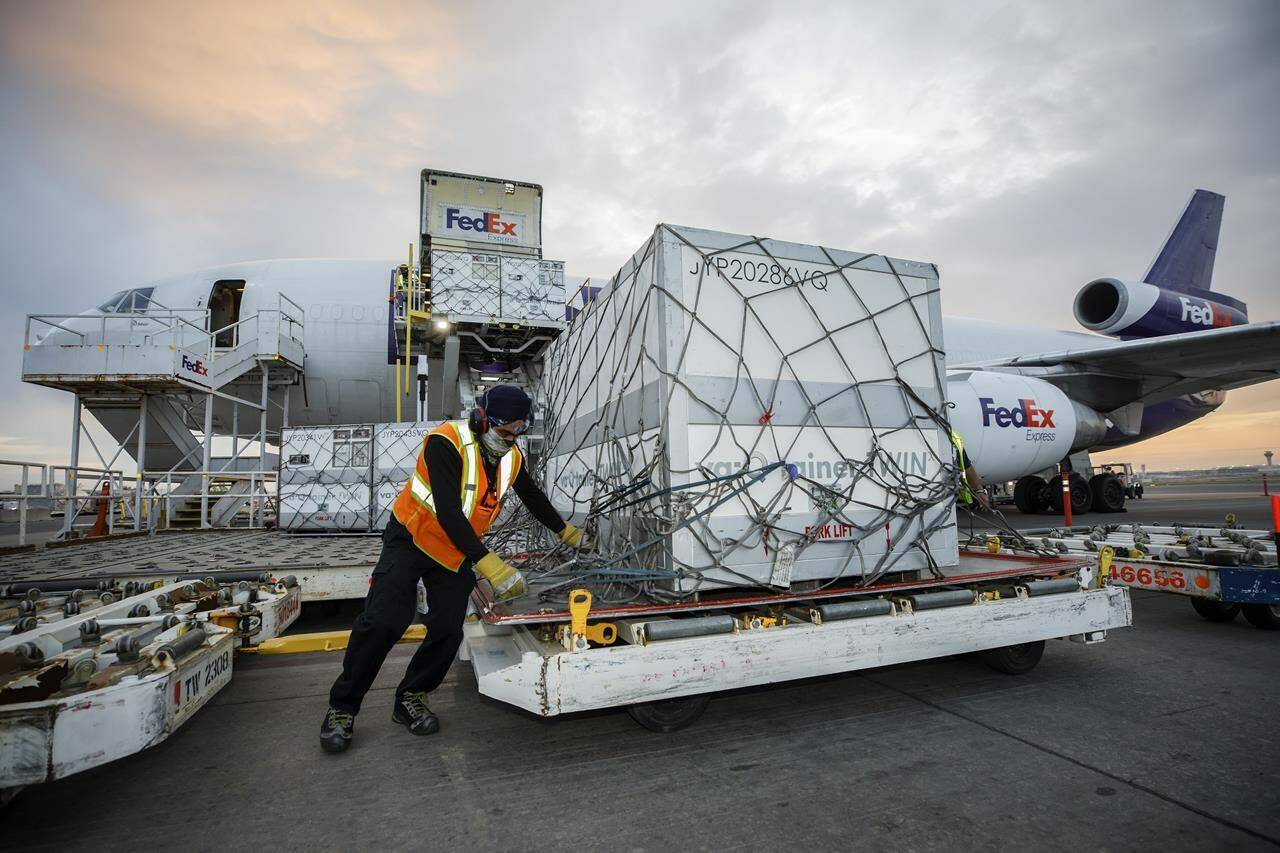 Workers unload a shipment of the Moderna COVID‑19 vaccine at the FedEx hub at Pearson International Airport in Toronto on May 20, 2021. Canada’s auditor general is expected to release two highly anticipated reports on the government’s handling of the COVID-19 crisis in 2021, including access to vaccines and pandemic benefits. THE CANADIAN PRESS/Cole Burston