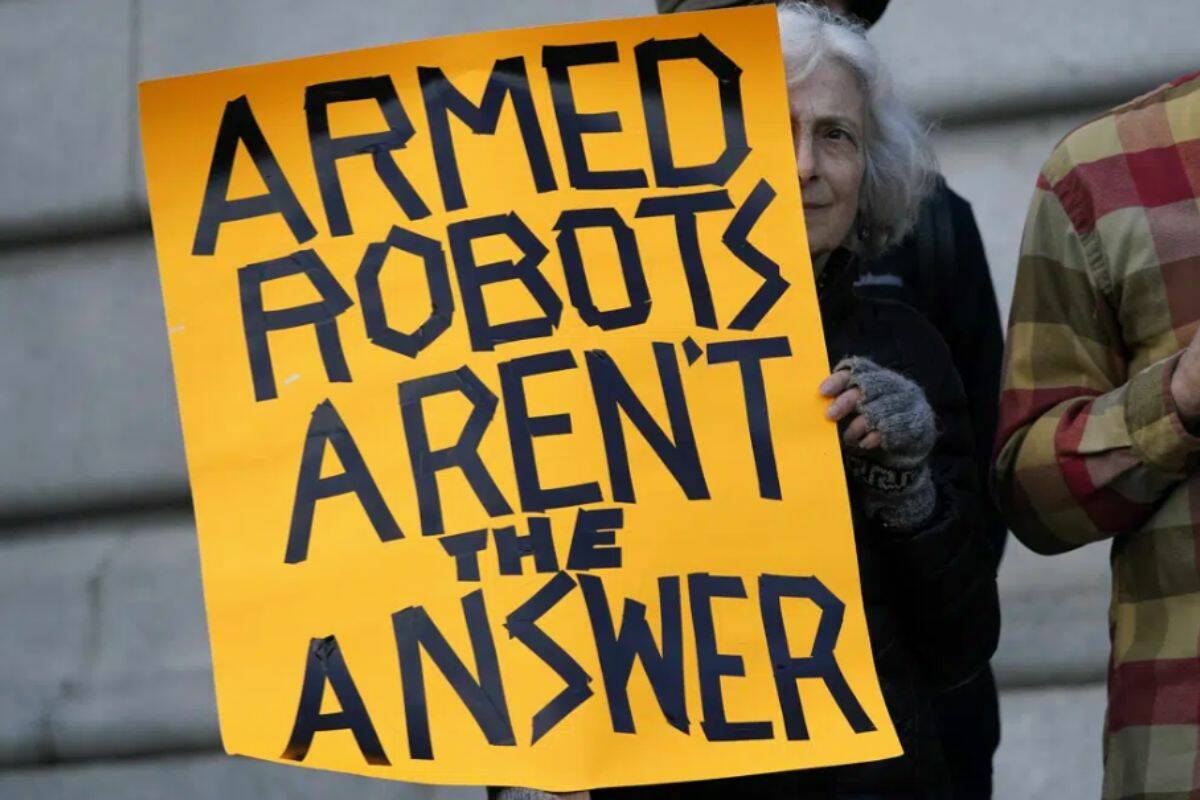 FILE - Diana Scott holds up a sign while taking part in a demonstration about the use of robots by the San Francisco Police Department outside of City Hall in San Francisco, Monday, Dec. 5, 2022. San Francisco supervisors have voted put the brakes on a controversial policy that would let police use robots for deadly force. The Board of Supervisors voted Tuesday to send the issue back to a committee for further discussion. (AP Photo/Jeff Chiu, File)